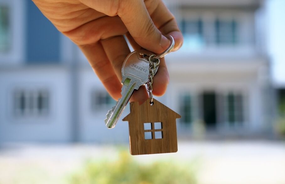 A hand holding a key and house-shaped keyring