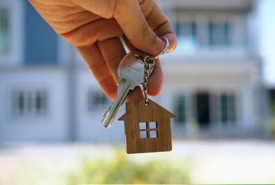 A hand holding a key and house-shaped keyring